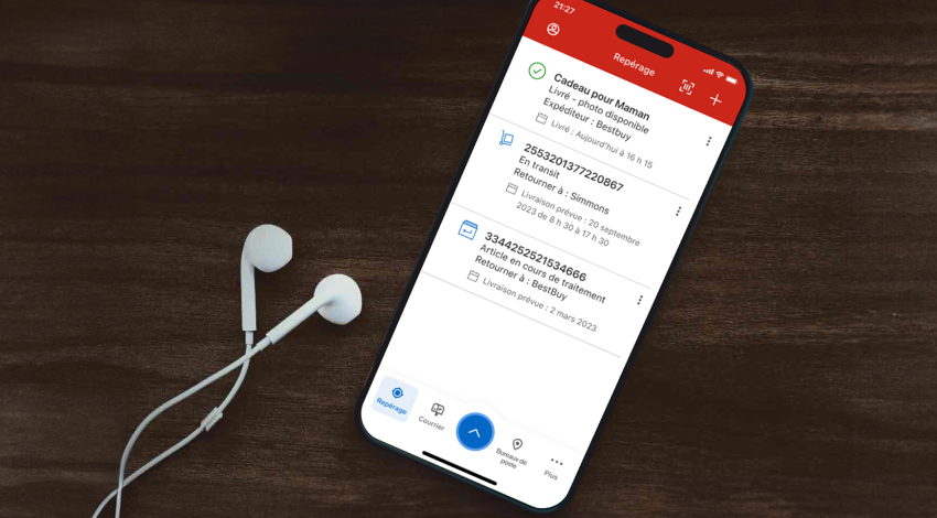 Un cellulaire est utilisé pour suivre des envois dans l’appli de Postes Canada. Des écouteurs sont posés à côté du cellulaire