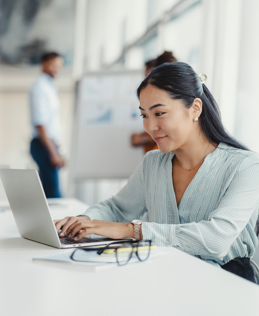 Une femme assise à une table de travail utilise un ordinateur portable